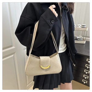 Model wearing beige suede baguette bag with gold crescent buckle and slim shoulder strap