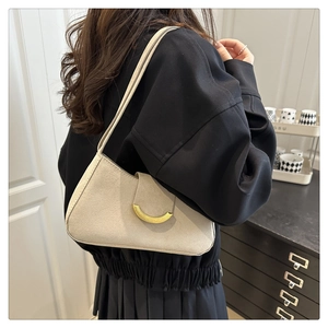 Détail de la texture suédée beige et boucle en métal doré sur le sac baguette élégant