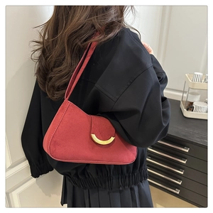 Detail of reddish-brown suede shoulder bag featuring a crescent gold metal buckle on a flap