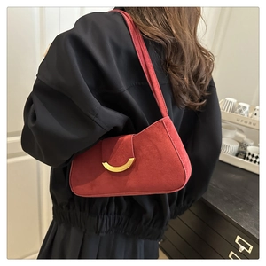 Close-up of burgundy suede baguette bag featuring a vintage crescent gold buckle detail