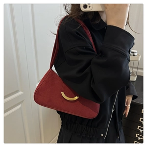 Detail of a vintage red suede underarm bag with a golden crescent clasp and strap