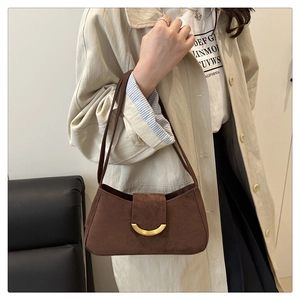 Detail of dark brown suede baguette bag with a stylish gold half-moon metal clasp buckle