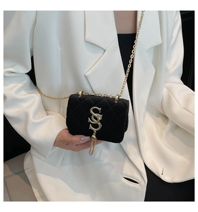 Modèle portant un sac bandoulière en velours noir avec chaîne dorée et gland décoratif