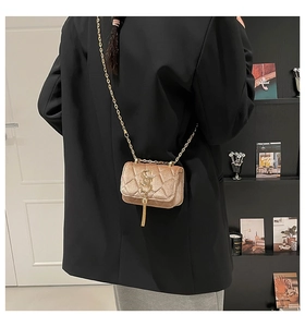 Détail du mini sac matelassé en velours avec pompon doré et fine chaîne en métal
