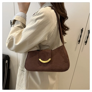 Detail view of brown suede shoulder bag with golden crescent metal buckle on a model