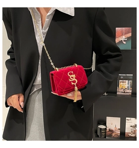 Détail du sac bandoulière en velours rouge avec logo S doré porté par un mannequin