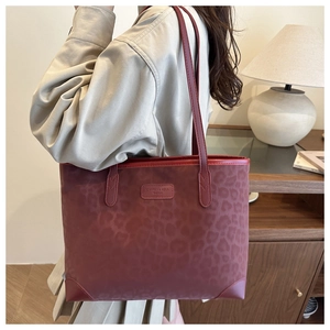 Detail of reddish brown faux suede tote with leopard pattern and leather logo label