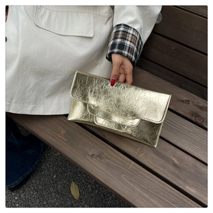 Detail der plissierten Metallic-Gold-Clutch mit strukturiertem Umschlag-Design