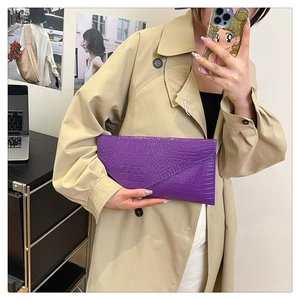 Detail of purple crocodile-pattern envelope clutch bag with textured PU leather finish