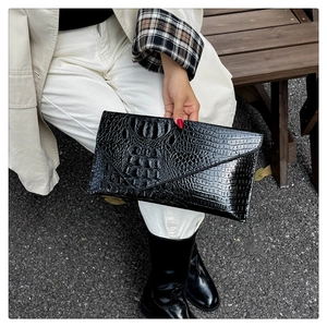 Close-up of black crocodile texture envelope clutch with glossy patent leather finish