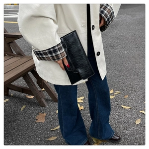 Schicke schwarze Leder-Clutch mit Textur, gestylt mit einem beigen Mantel für Damen