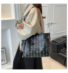 Detail of bear pattern print on black tote bag with brown leather strap and brand patch