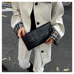Detailaufnahme der schwarzen Briefumschlag-Tasche mit Krokodilmuster und Lederstruktur
