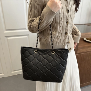 Schwarze gesteppte Shopper-Tasche mit Kettenriemen von einem Model in Innenraum getragen