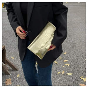 Detailansicht der champagnergoldenen Clutch mit Metallic-Textur und geschwungenem Design