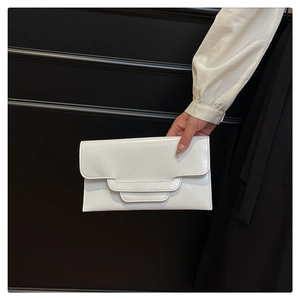 Detail einer weißen glänzenden PU-Leder-Clutch mit modischem Faltdesign von einem Model