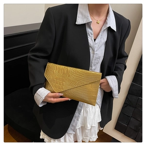 Detail der goldenen Umschlag-Clutch mit Krokoprägung kombiniert mit Business-Outfit