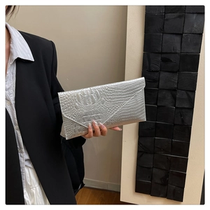 Makroansicht der silbernen Umschlag-Clutch mit Krokoprägung, von einem Model gehalten