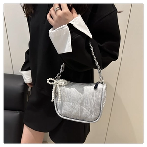 Détail du sac à main plissé argenté avec chaîne et nœud en perles sur le mannequin