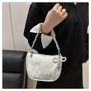 Détail du tissu à texture marbrée blanche avec chaîne argentée et charm nœud perlé