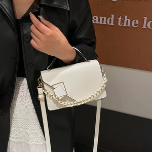 White crossbody bag with metallic square buckle and woven chain handle on a model