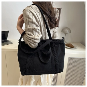 Detail of black corduroy tote bag with dual straps shown in a cozy office setting