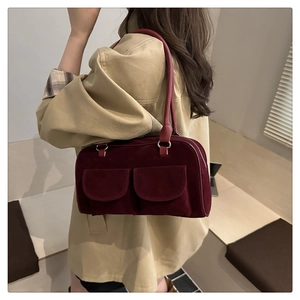 Detail of burgundy suede shoulder bag with dual pockets and silver ring hardware
