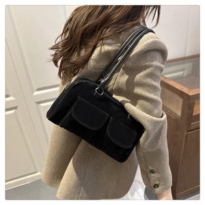 Détail du sac sous le bras en daim noir avec poches décoratives à rabat et fine bandoulière