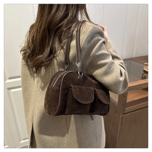 Close-up of dark brown suede shoulder bag with dual front flap pockets and zipper