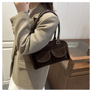 Détail du sac bandoulière en daim marron foncé avec deux poches avant et anses longues
