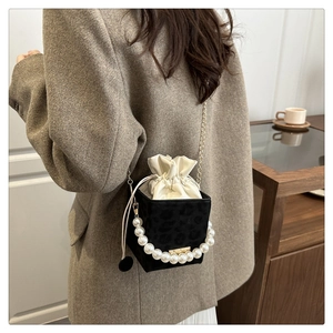 Detail of leopard print cube bag featuring pearl chain strap and drawstring closure