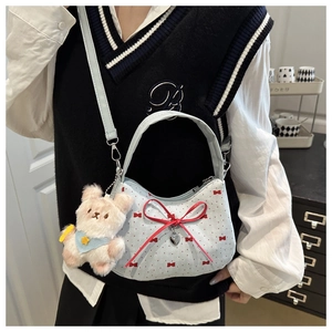 Détail du sac bandoulière bleu clair avec nœuds rouges et charmant ourson blanc