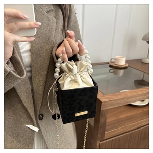 Detail of black leopard texture bag with pearl handle and gold chain strap on table