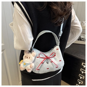 Détail du sac croissant bleu clair avec un grand nœud rouge et un pendentif coeur
