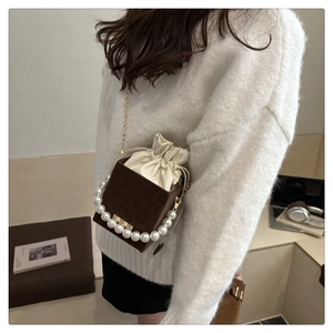 Detail of leopard print bucket bag featuring a white pearl handle and gold chain strap