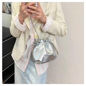 Detail of silver metallic cloud bag with drawstring closure and slim shoulder strap