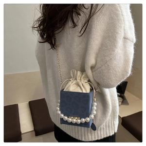 Detail of blue leopard print bucket bag with pearl handle and metal chain strap