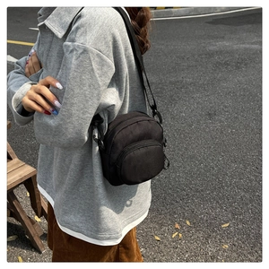 Outdoor shot showing the size and fit of a black nylon mini crossbody bag for women