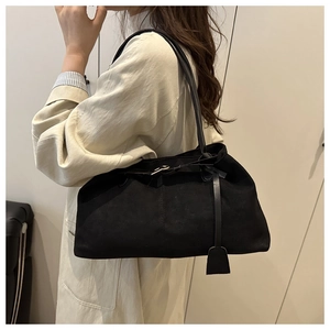 Detail of minimalist black matte tote bag with leather strap shown on a model