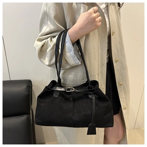 Détail d'un cabas noir en daim avec boucle dorée et bandoulière en cuir haut de gamme