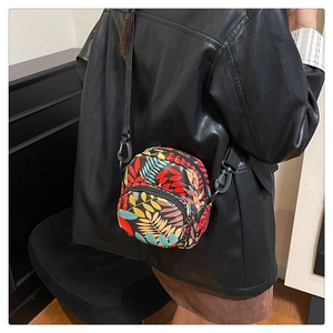 Side view of woman wearing compact crossbody bag with vibrant colorful leaf pattern
