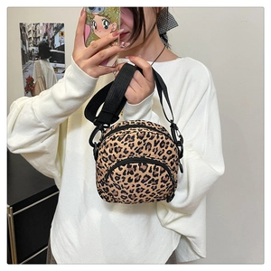 Detail of leopard print crossbody bag featuring double zippers and a wide nylon strap