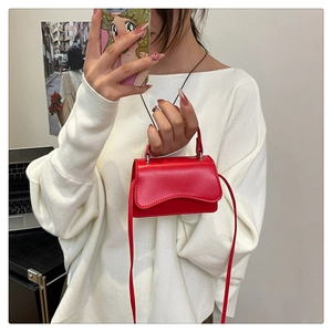 Macro detail of red glossy leather mini handbag with wavy flap design and slim shoulder strap