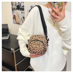 Detail of leopard print crossbody bag with dual zippers and adjustable strap