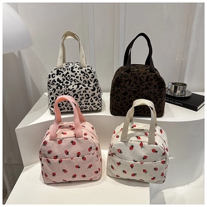 Detail of four corduroy lunch bags featuring leopard and strawberry prints with front pockets