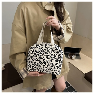 Detail of leopard print corduroy handbag featuring cream canvas handles and a front pocket