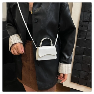 Detail of white mini crossbody bag with round handle on a chic vintage outfit