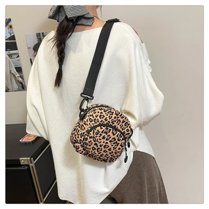 Detail showing the adjustable wide strap and round zip pocket of leopard print crossbody bag