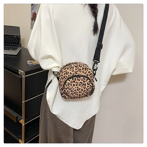 Detail of a leopard print crossbody bag worn by a model in a casual lifestyle setting