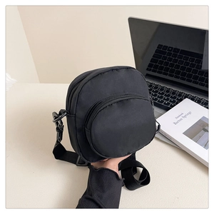 Close-up of compact black nylon crossbody bag with multi-zipper pockets and adjustable strap